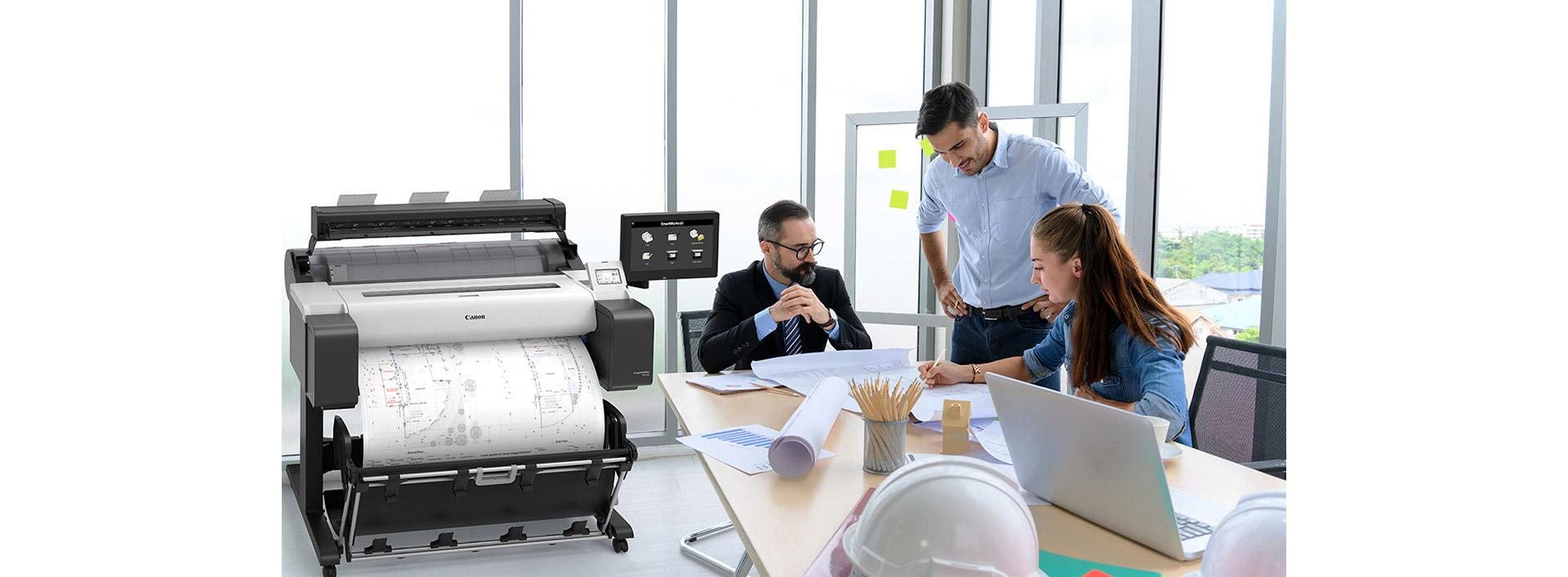 Une équipe de trois architectes consulte des plans pendant qu’une nouvelle série est imprimée avec une imprimante grand format Canon imagePROGRAF TM-305.