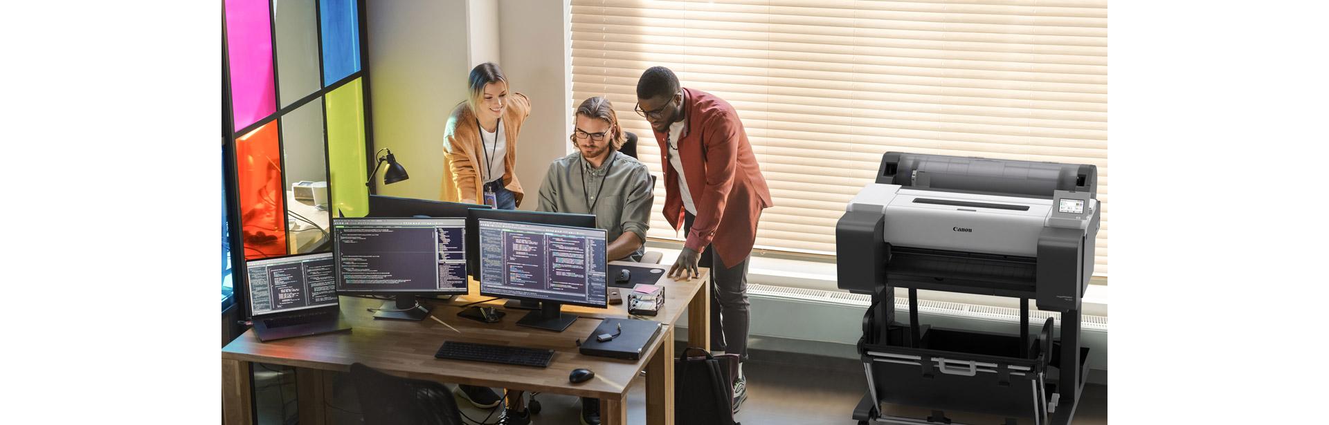 Trois collègues travaillant autour d’un bureau. L’imprimante grand format Canon imagePROGRAF TM-255 est posée à côté d’eux.
