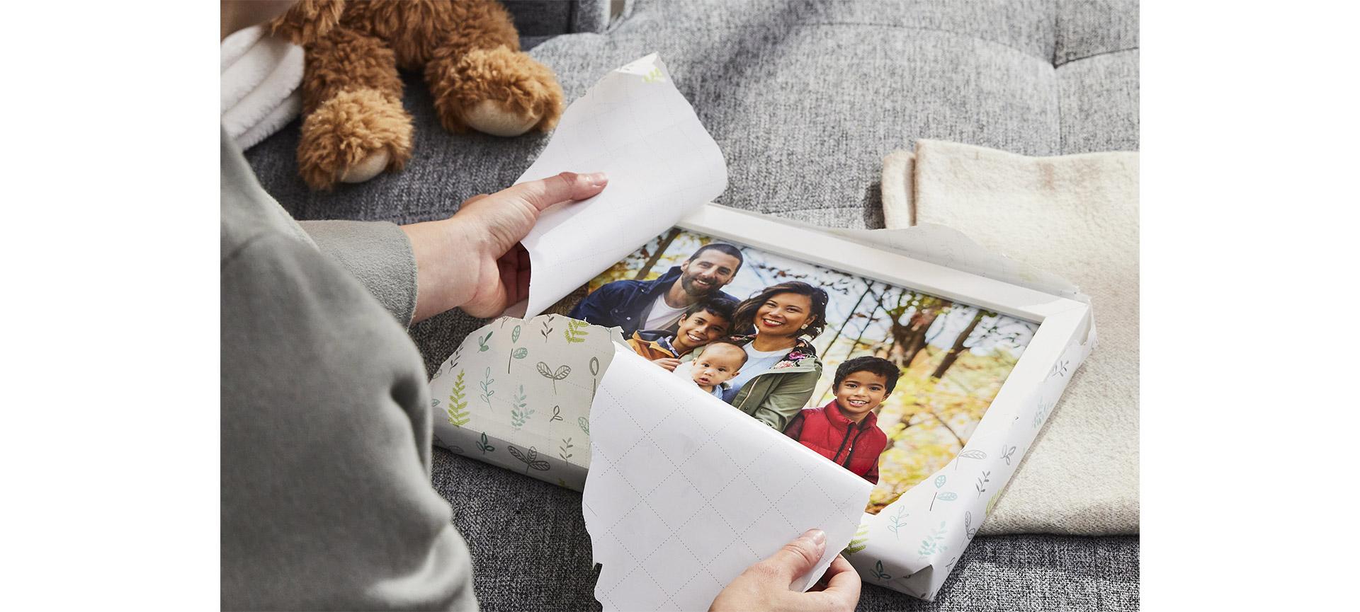 Woman unwrapping framed photo given as gift.