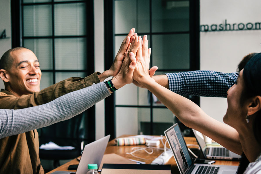 Businessmen and businesswomen high-fiving in group meeting