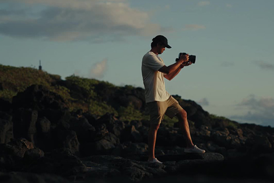 Zak Noyle en train de filmer debout sur une falaise rocheuse